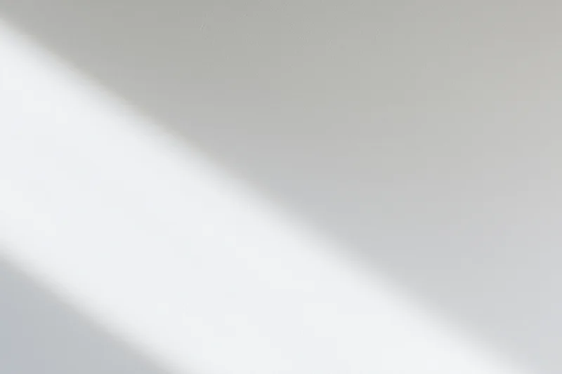 Diagonal band of natural light across a plain white interior surface