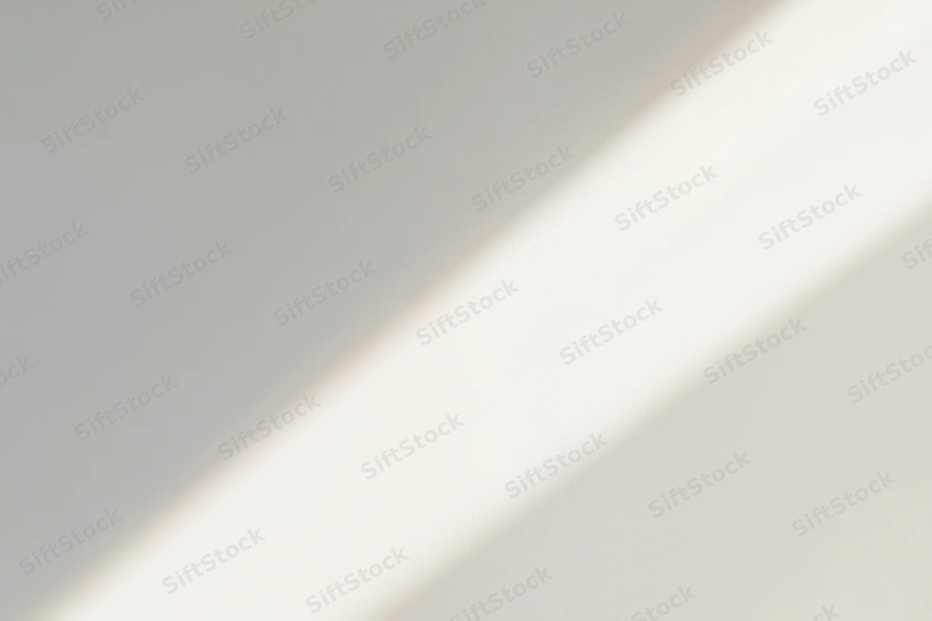 Diagonal band of natural sunlight falling across a plain gray interior surface