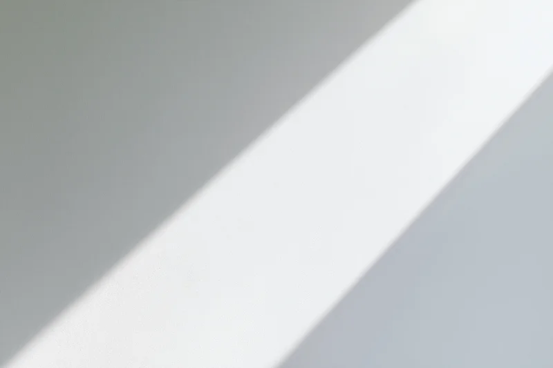 Diagonal band of natural window light falling across a plain gray surface