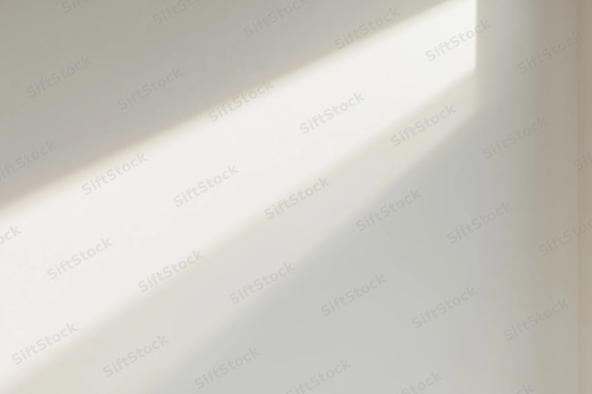 Diagonal strip of natural window light falling across a plain white wall