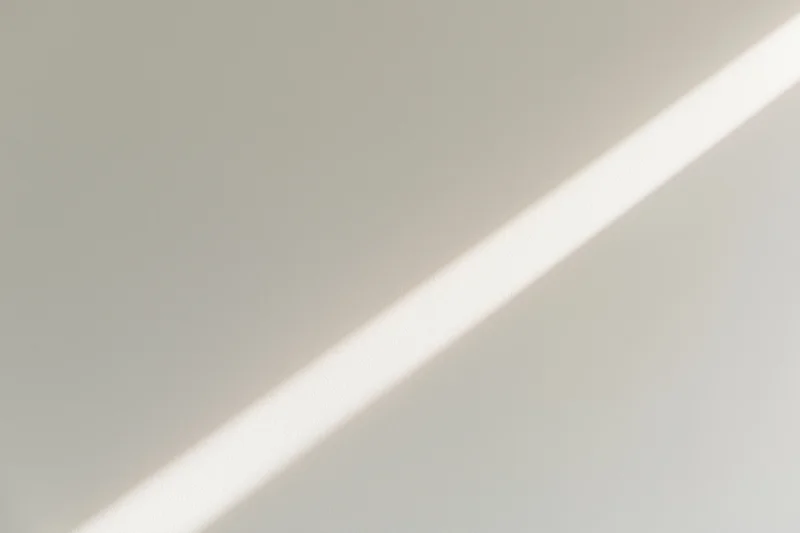 Diagonal strip of natural window light across a plain indoor surface