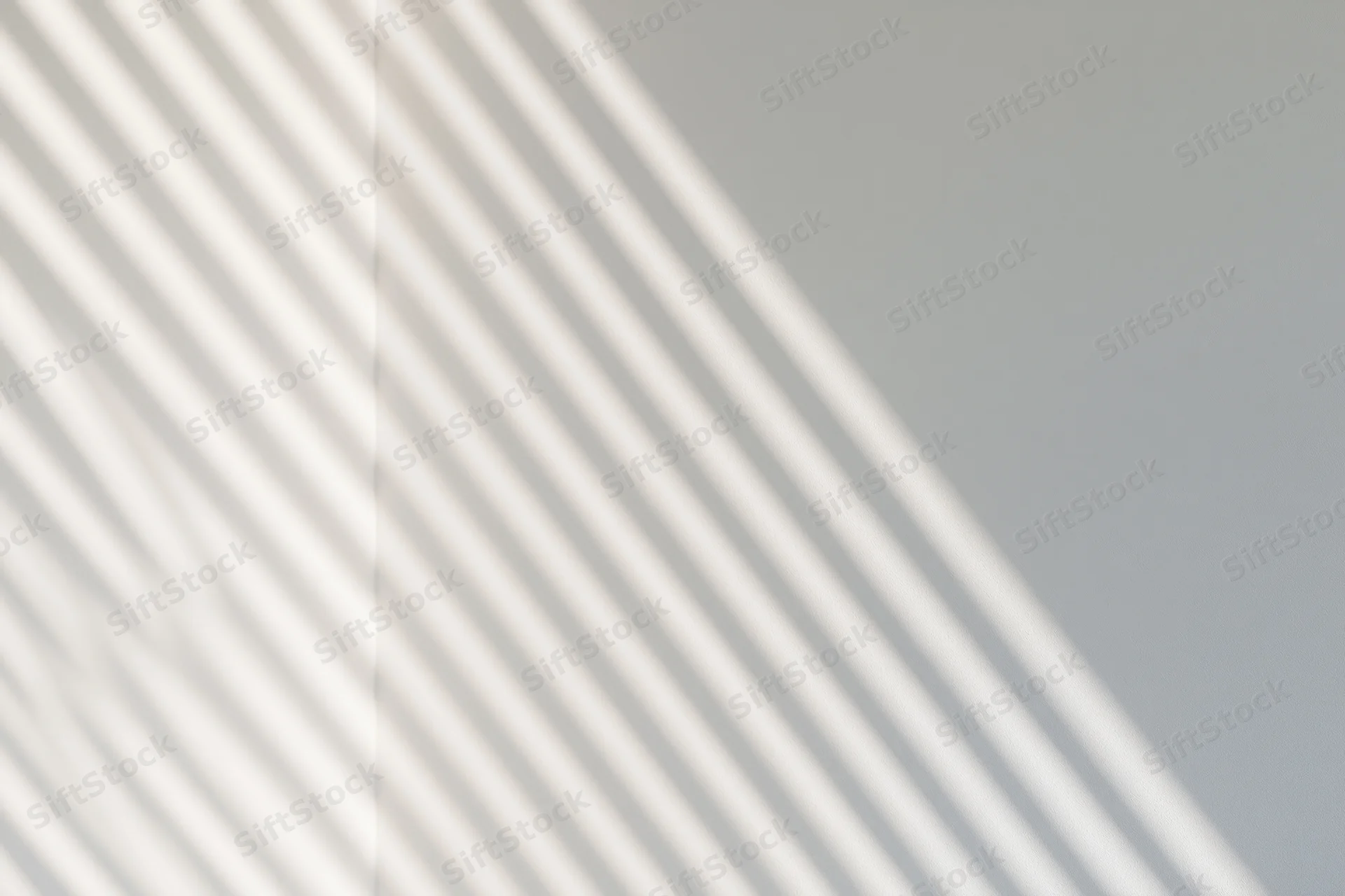 Diagonal shadow stripes from window blinds on a plain wall