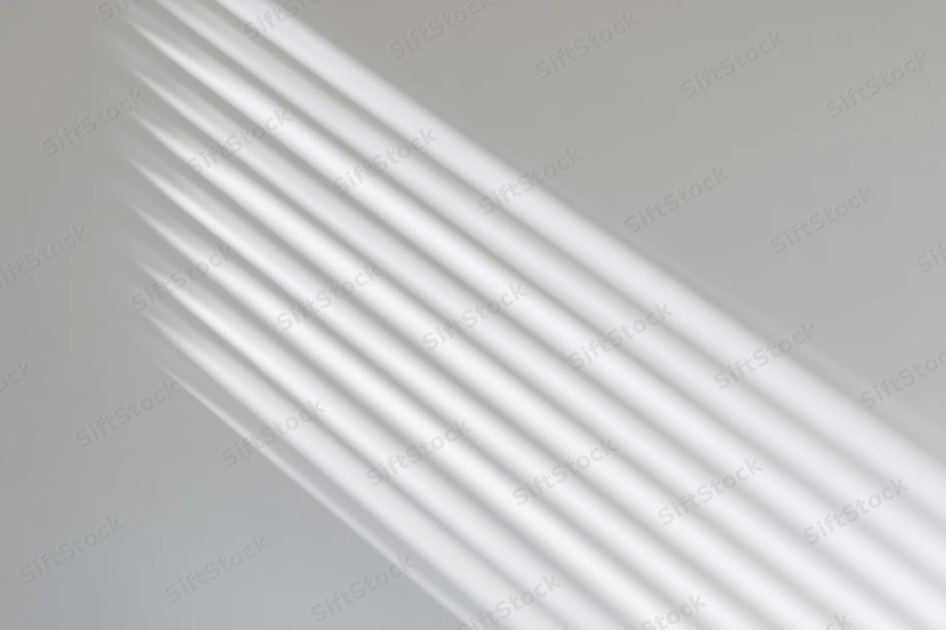 Diagonal light streaks from window blinds on a plain wall