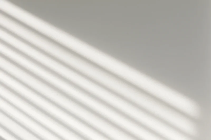 Diagonal light stripes from window blinds on a plain wall
