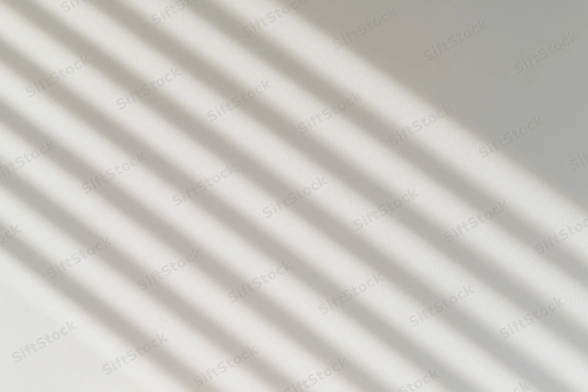 Diagonal light and shadow stripes across a plain wall surface