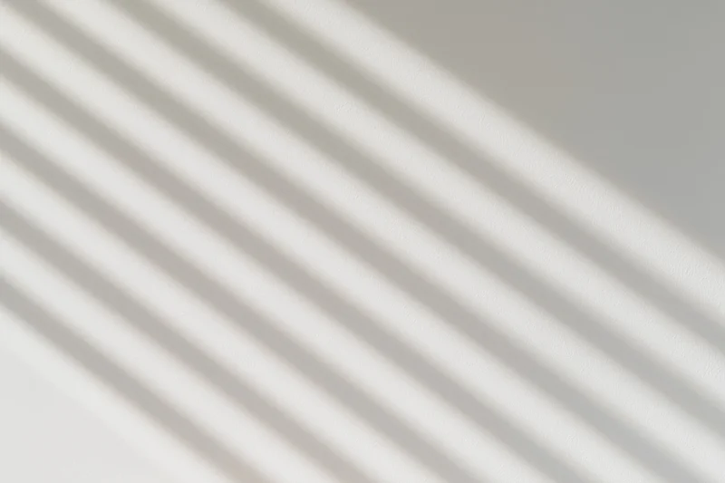 Diagonal light and shadow stripes across a plain wall surface