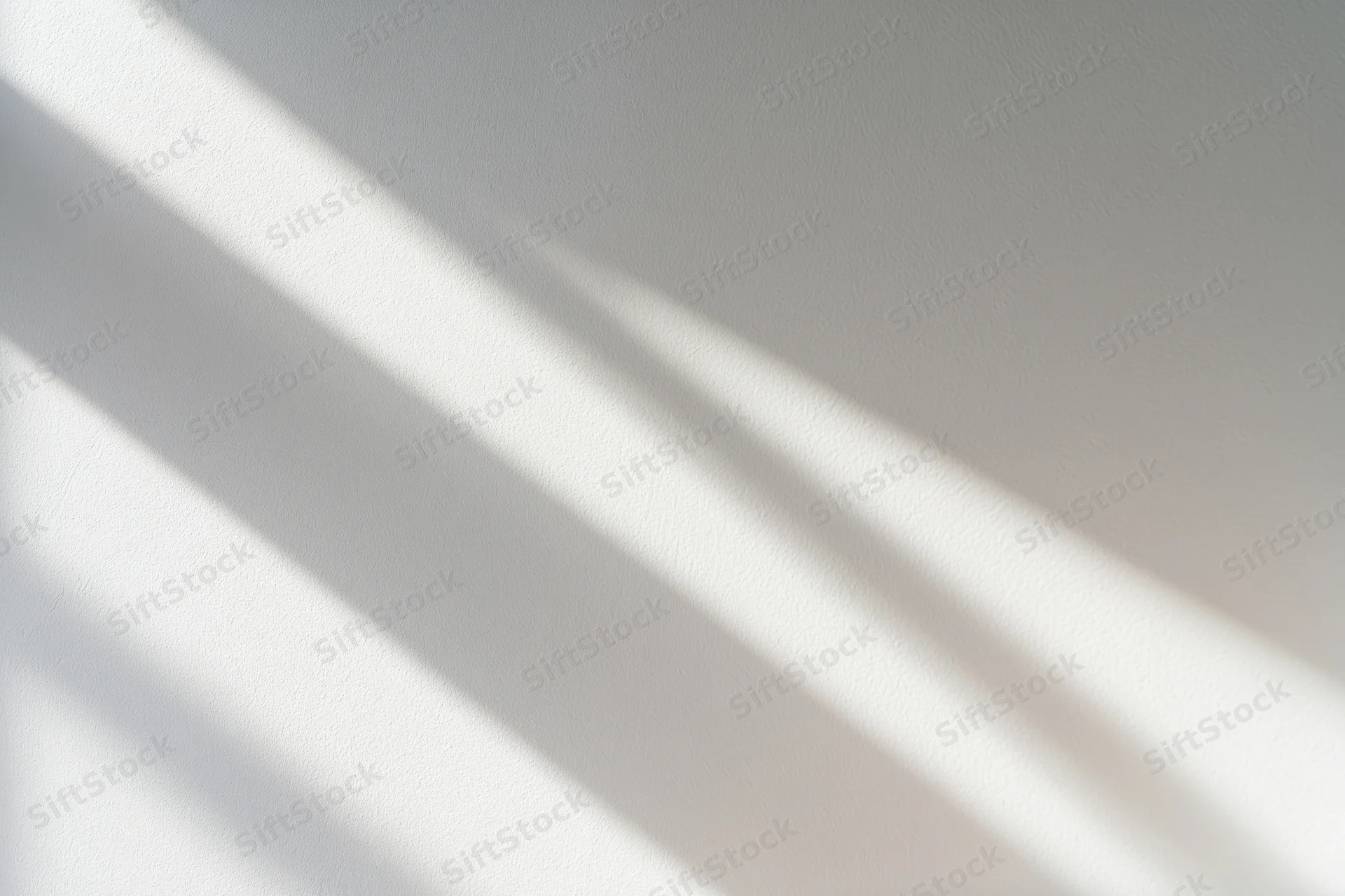 Diagonal light beams casting soft overlapping shadows on a white wall