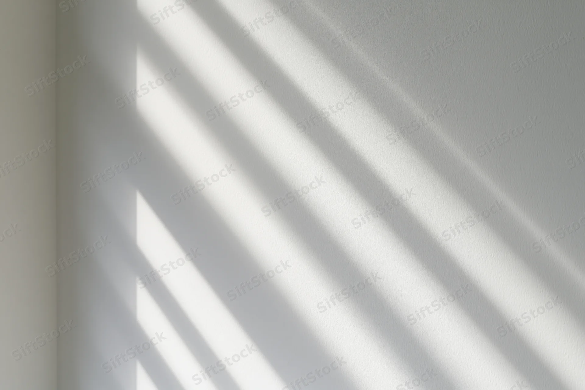 Diagonal light bands cast by window blinds on a white interior wall