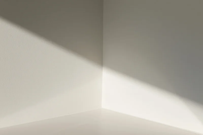Diagonal sunlight casting a soft shadow across a white interior corner