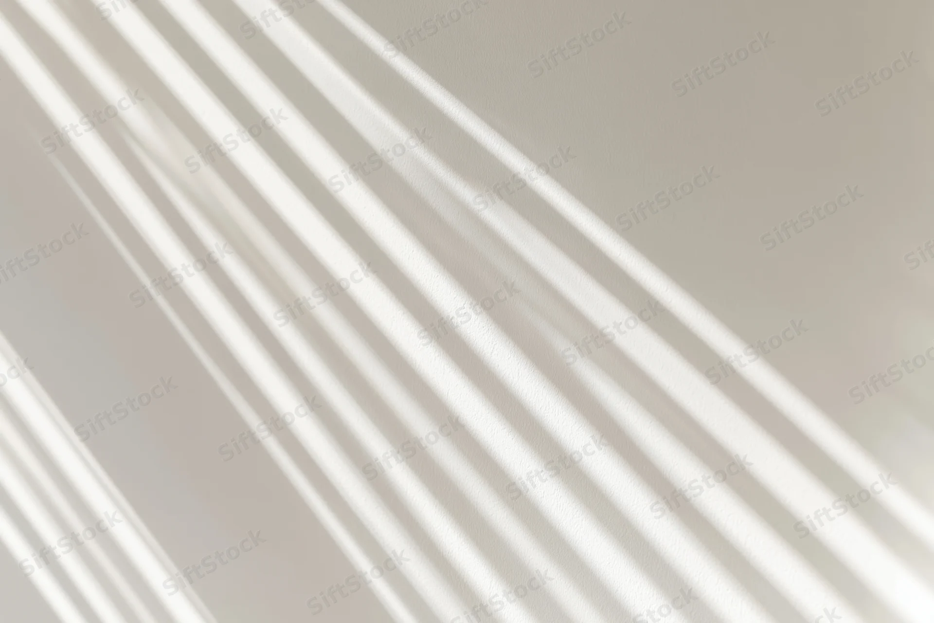 Diagonal light stripes casting soft shadows on a neutral wall indoors
