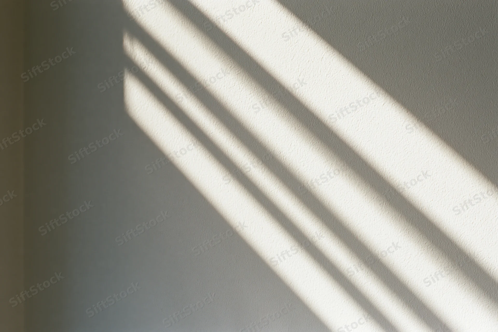Diagonal sunlight shadow pattern on a plain off-white interior wall