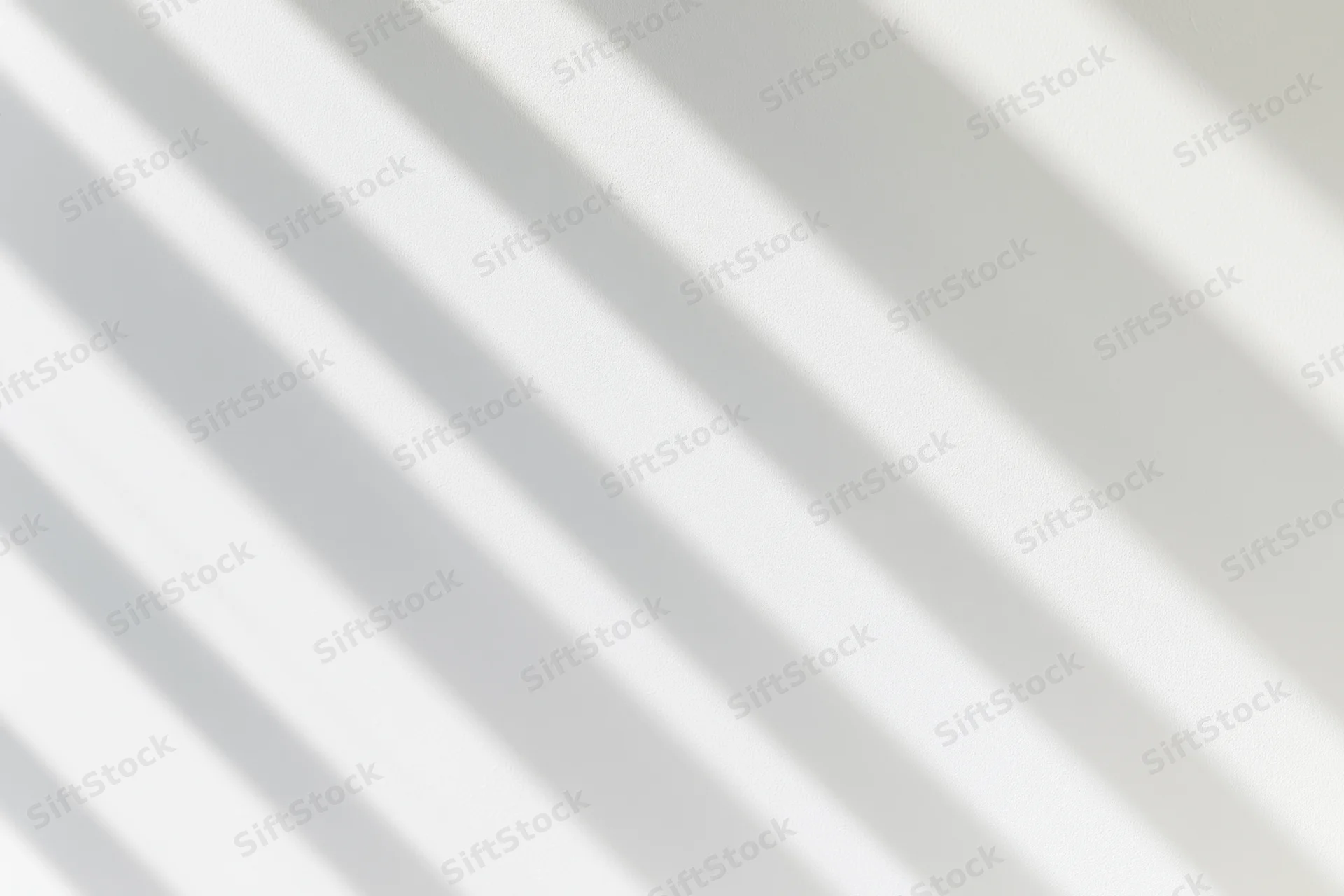 Diagonal shadow lines from window light on a white wall