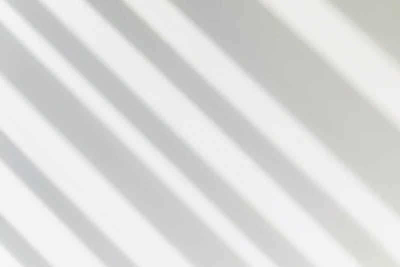 Diagonal shadow lines from window light on a white wall