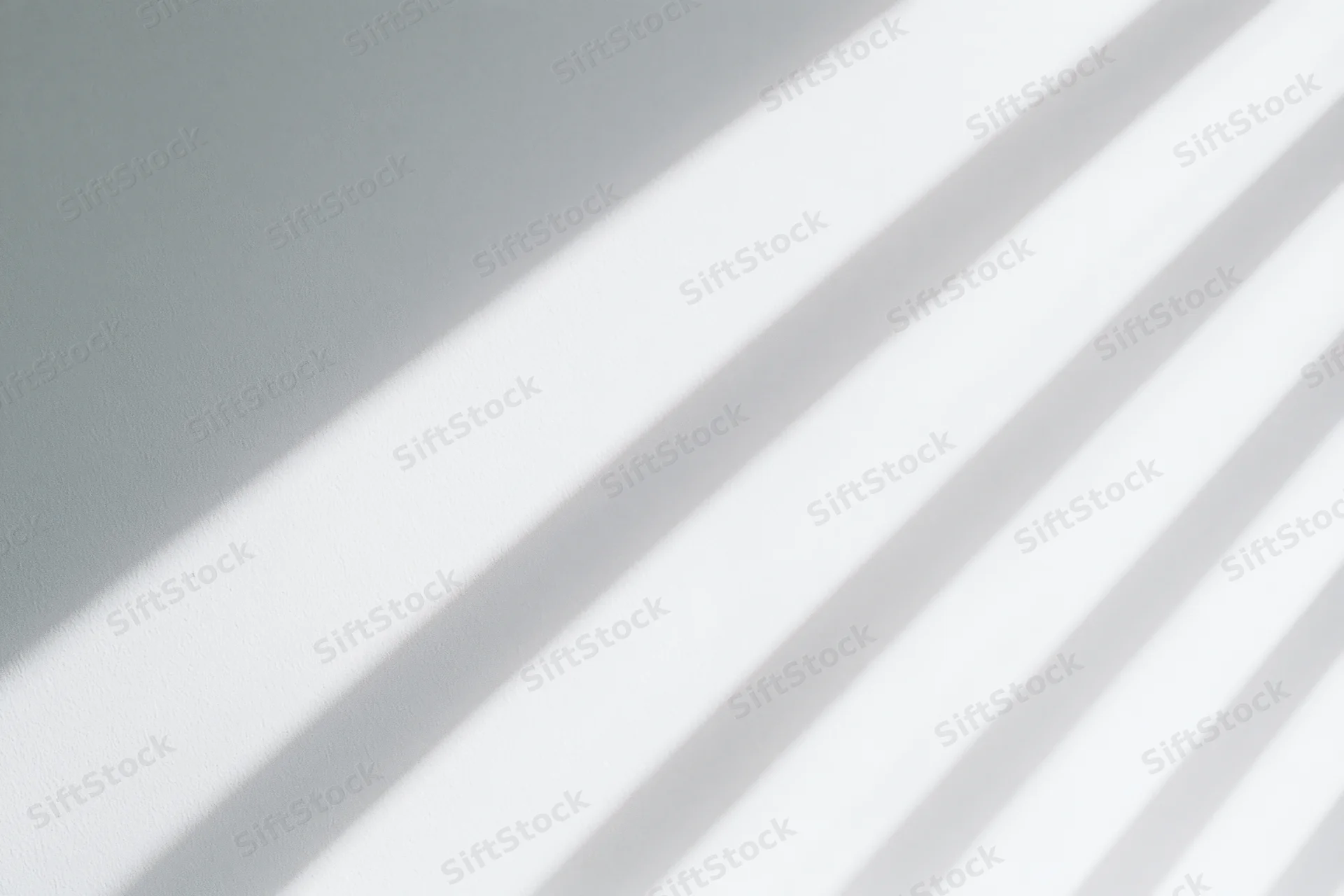 Diagonal light and shadow stripes across a plain white interior wall