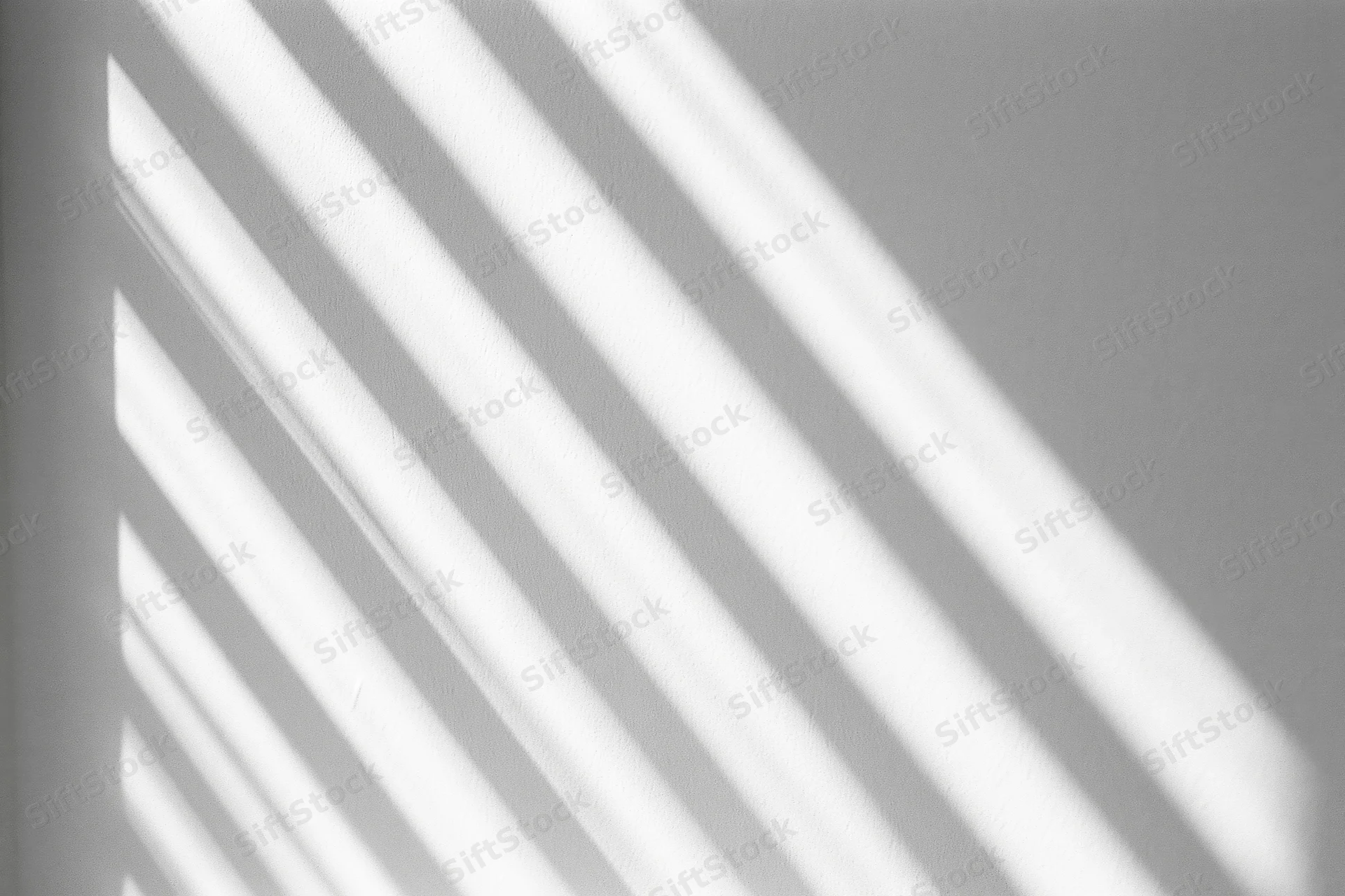 Diagonal light and shadow stripes cast across a plain white interior wall