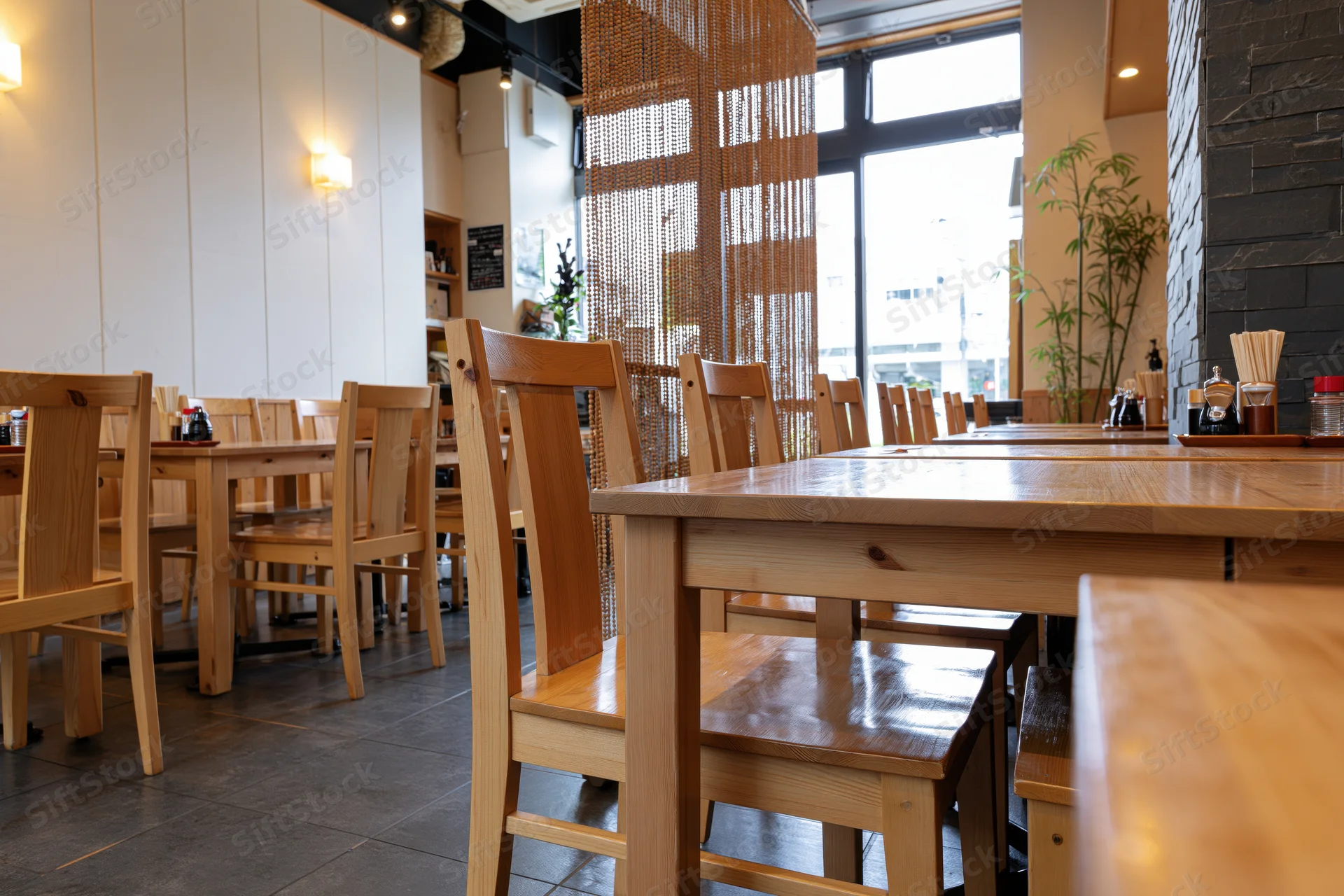 Empty wooden tables and chairs arranged in a modern Japanese casual restaurant dining area