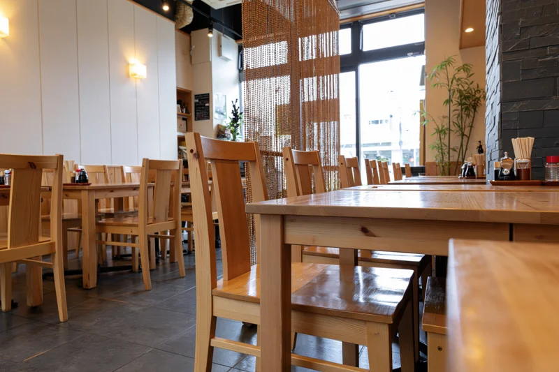 Empty wooden tables and chairs arranged in a modern Japanese casual restaurant dining area