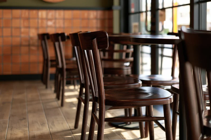 Empty cafe interior with dark wooden chairs and round tables arranged in rows near windows