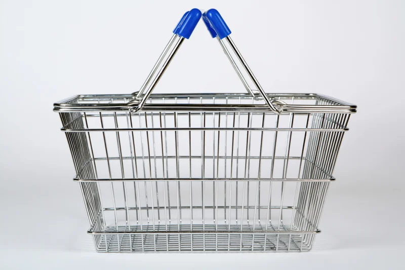 Empty chrome wire shopping basket with raised blue-handled grips isolated on white background