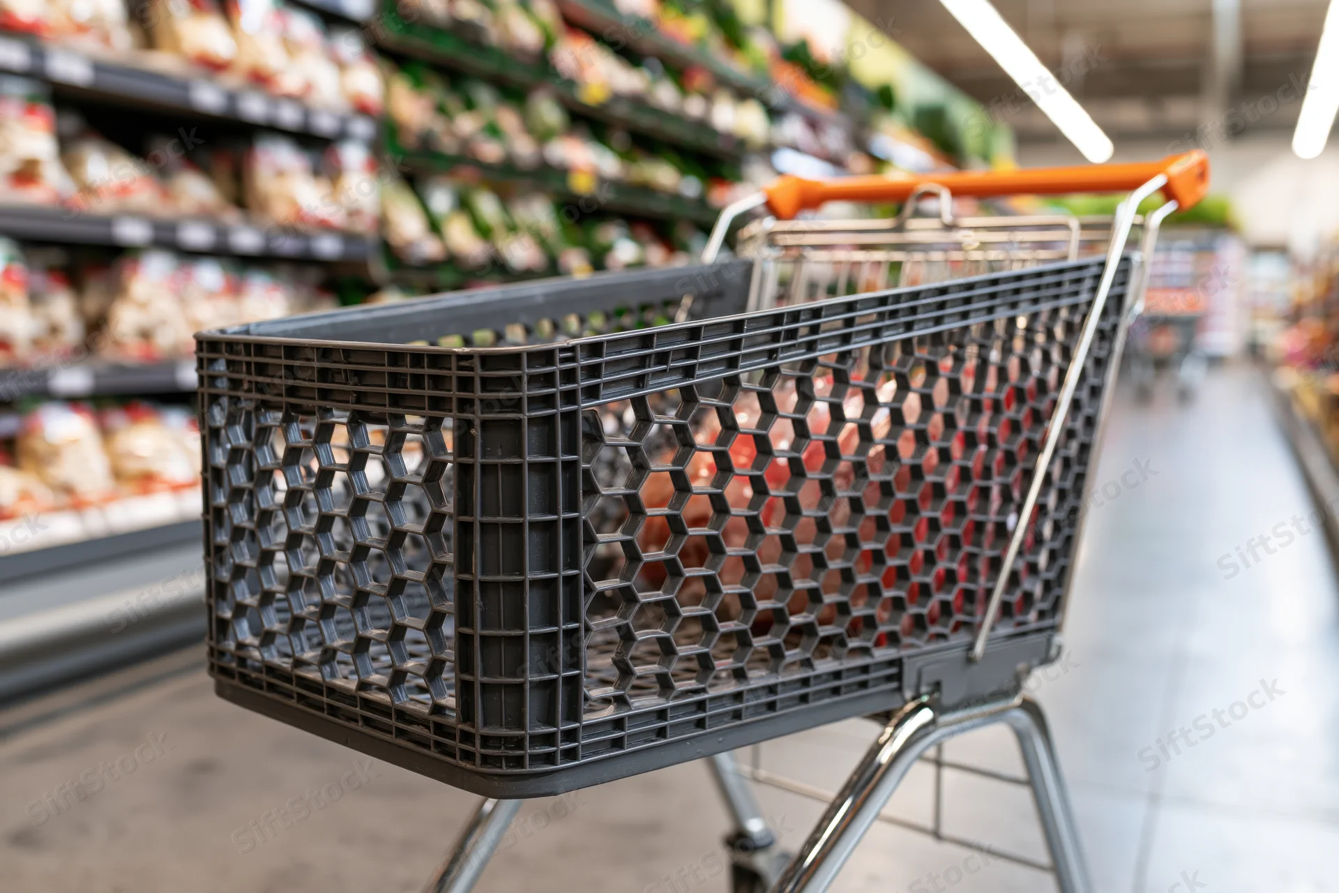 Empty dark grey plastic shopping cart with orange handle in a supermarket aisle