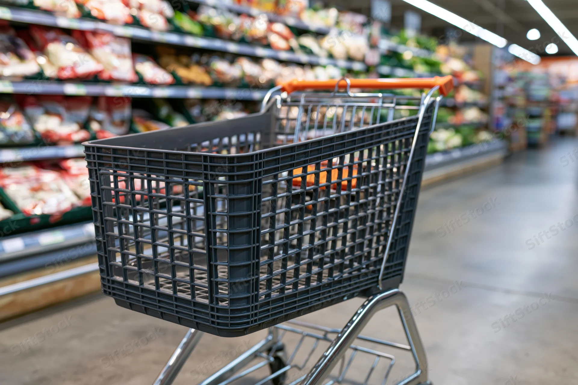 Empty dark grey plastic shopping cart with orange handle in a supermarket produce aisle