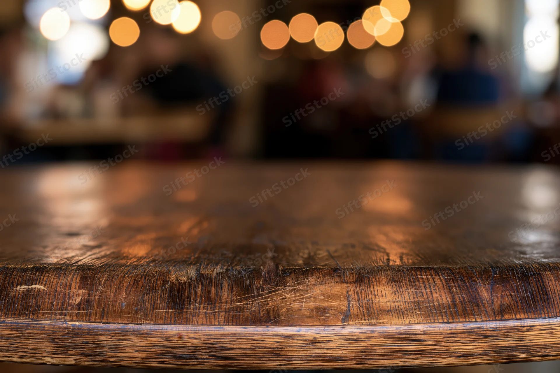 Close-up of a dark wooden table surface in a dimly lit restaurant with blurred patrons and warm bokeh lights in the background