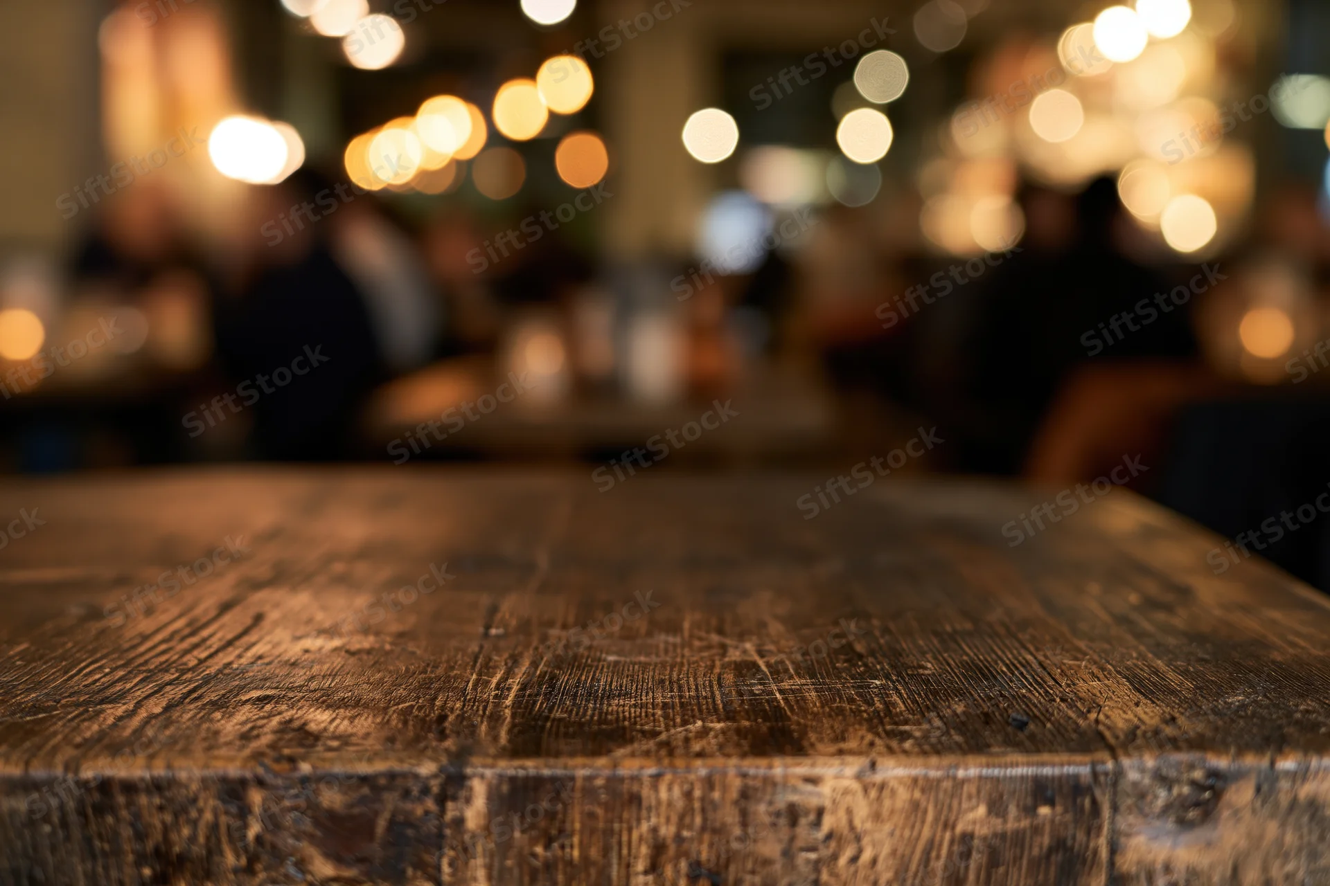 Dark wooden table surface in sharp focus with blurred restaurant background and warm bokeh lights