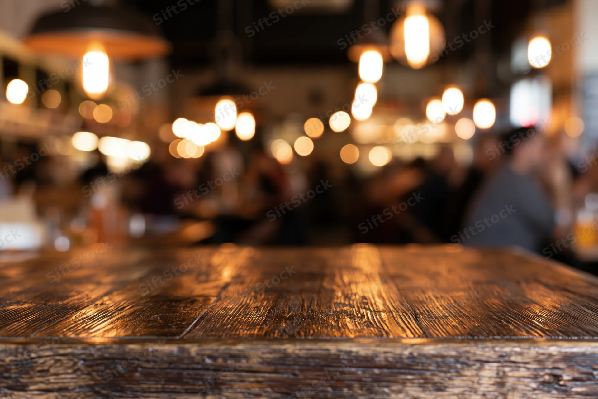 Dark wooden table in focus with blurred restaurant interior and warm lights in background