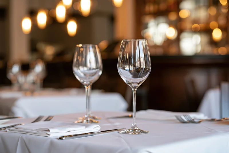 Fine dining table set with wine glasses and cutlery on white linen in a restaurant interior