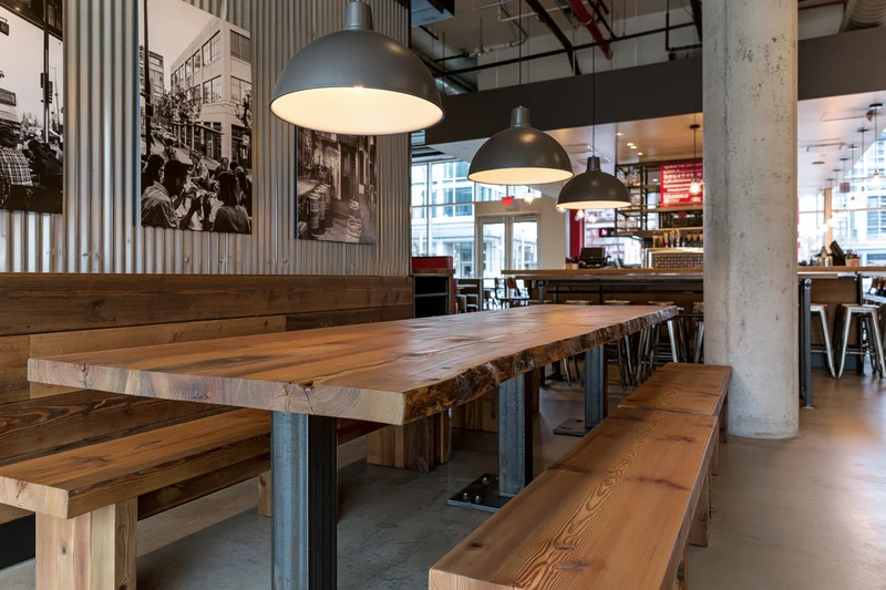 Long wooden table with benches under pendant lights in industrial restaurant interior