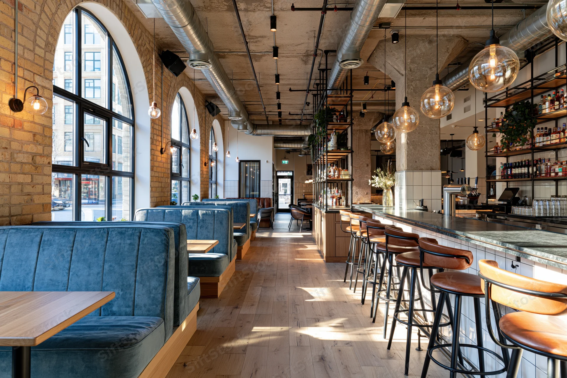 Empty industrial-style restaurant interior with booth seating and bar counter