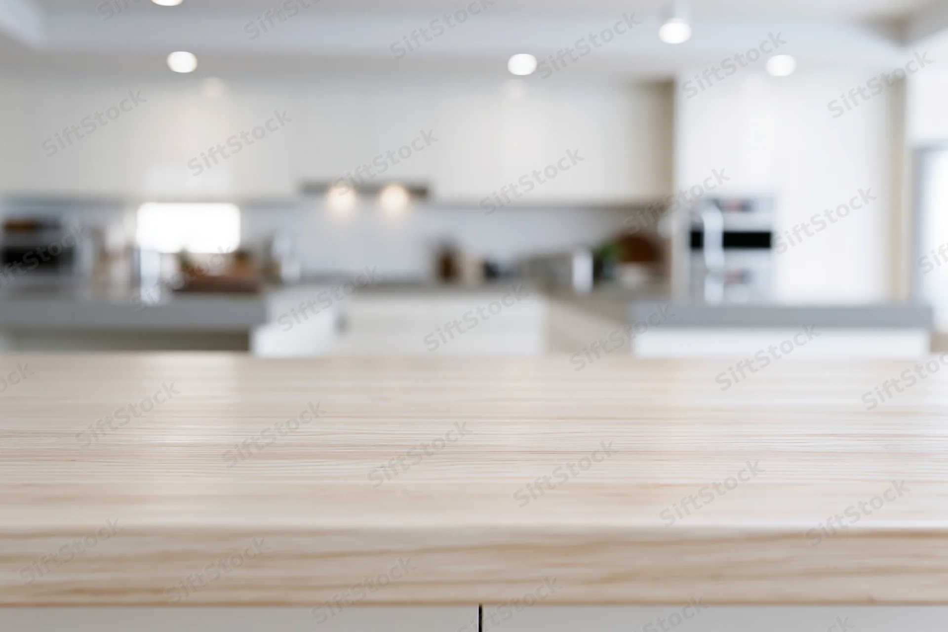 Light wood countertop in sharp focus with blurred kitchen interior behind