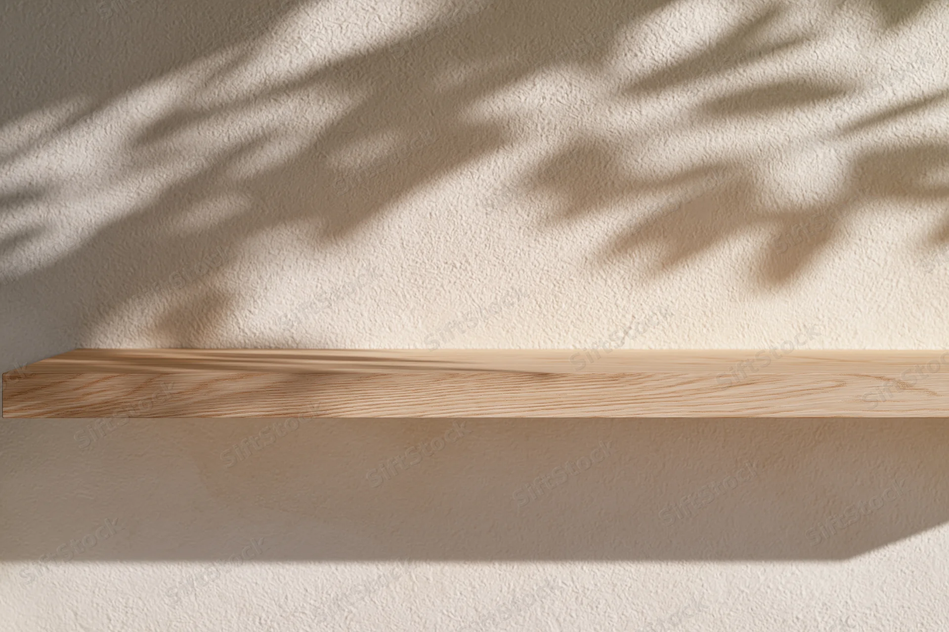 Light wood shelf mounted on textured plaster wall with dappled leaf shadows