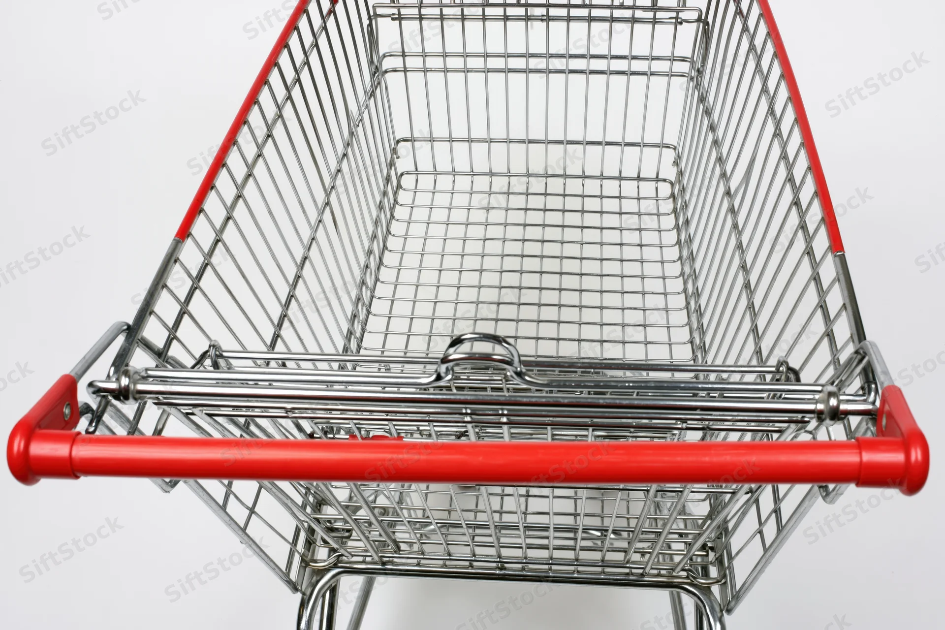 Empty metal shopping cart viewed from above with red handle against white background