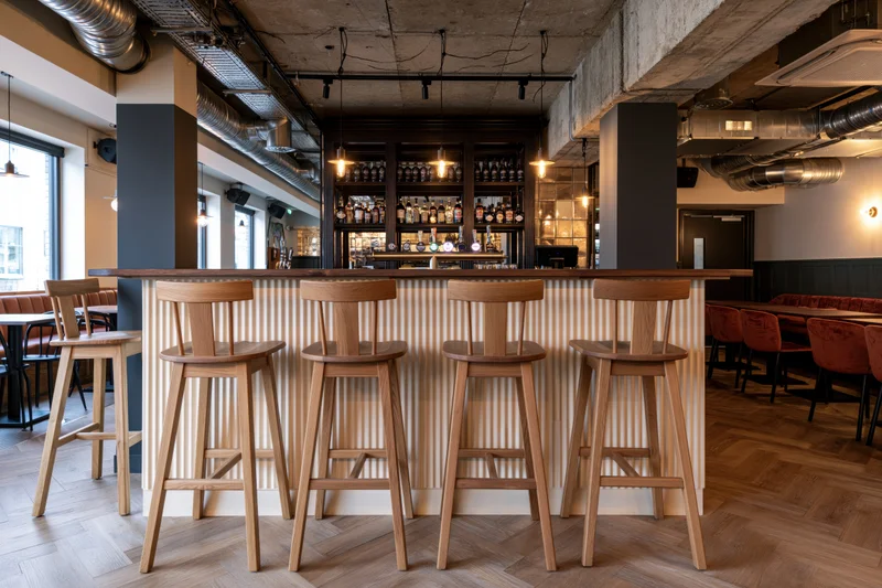 Modern gastropub interior with wooden bar stools and exposed industrial ceiling features