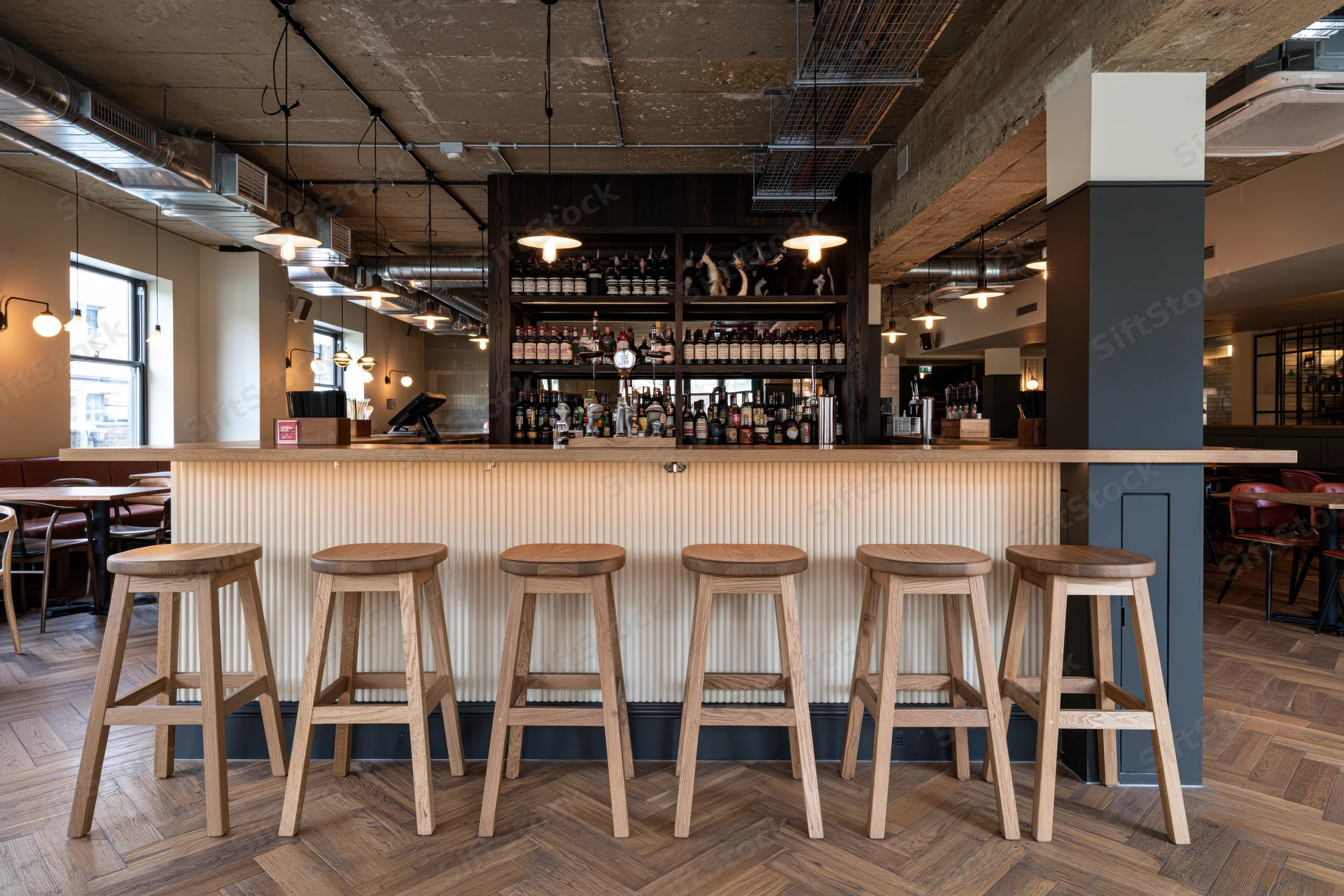 Modern gastropub bar interior with wooden stools and exposed industrial ceiling features