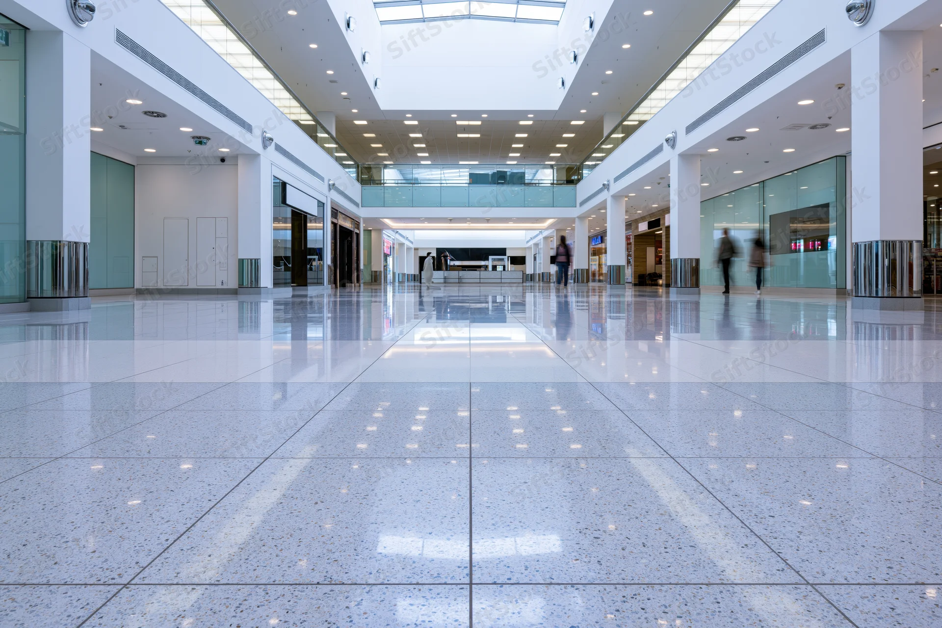 Wide view of empty modern shopping mall atrium with reflective tiled floor and glass walls