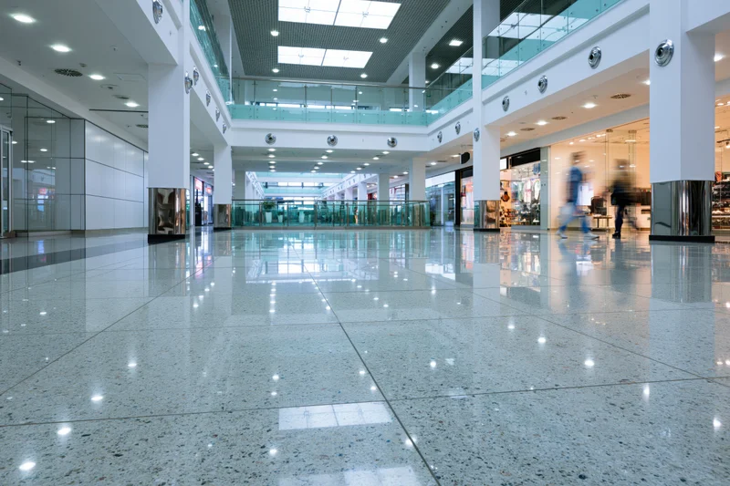 Wide view of modern shopping mall atrium with polished tile floor and glass railings on multiple levels