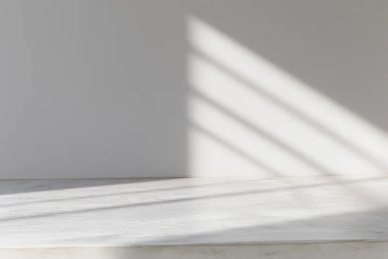 Polished concrete tabletop with diagonal light and shadow patterns from a window, in a minimalist interior