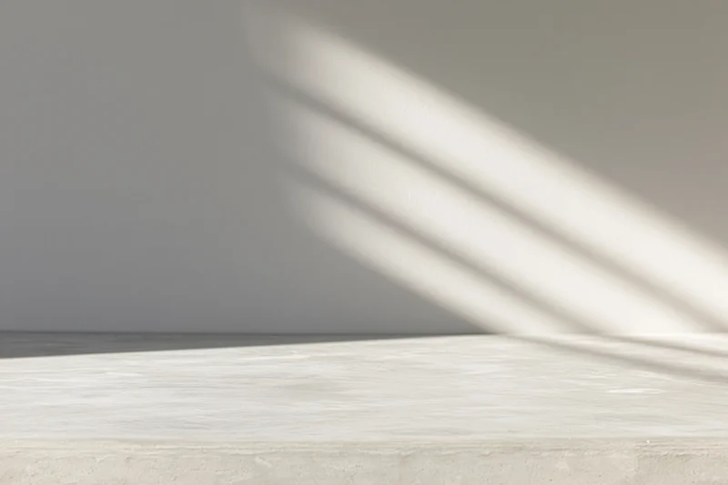 Polished concrete tabletop with light stripes from window blinds in minimalist interior