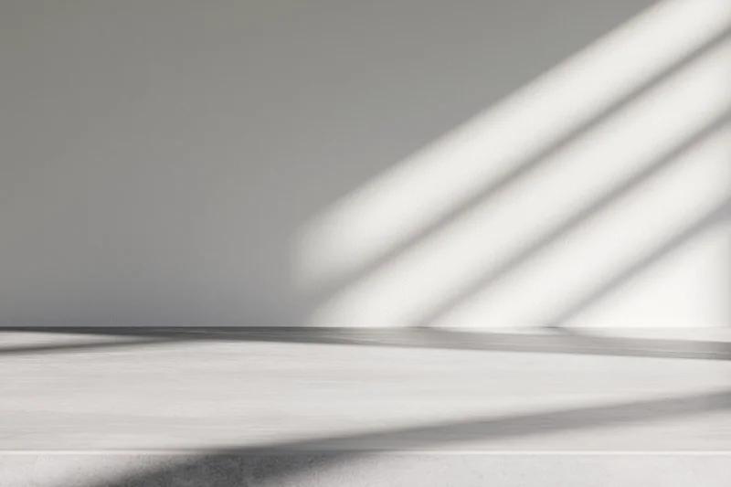 Polished concrete table surface with diagonal light shadows in a minimalist interior