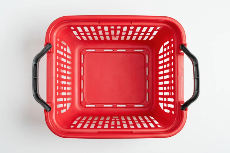 Empty red plastic shopping basket viewed from above on white background