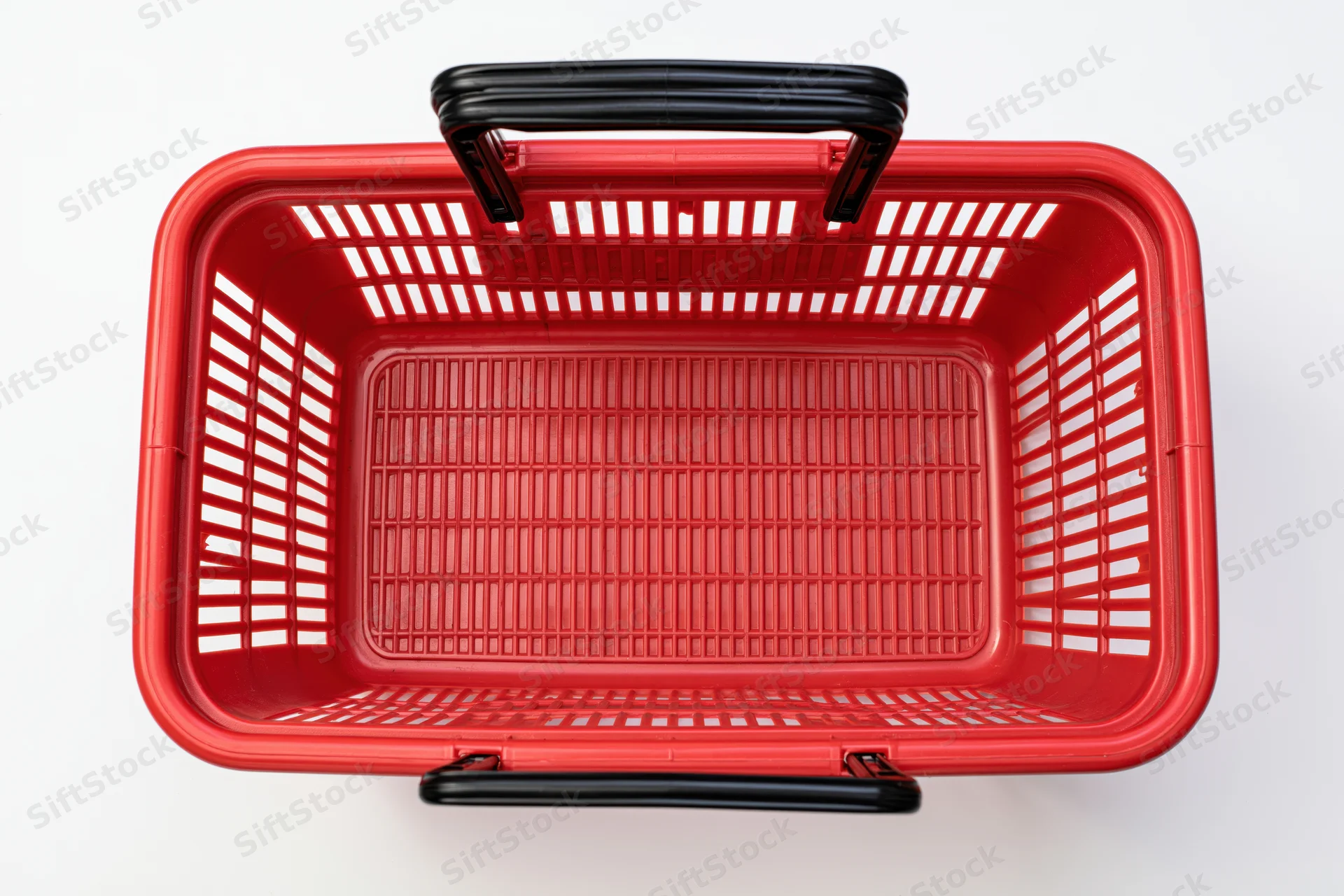 Empty red plastic shopping basket with black handles on white background