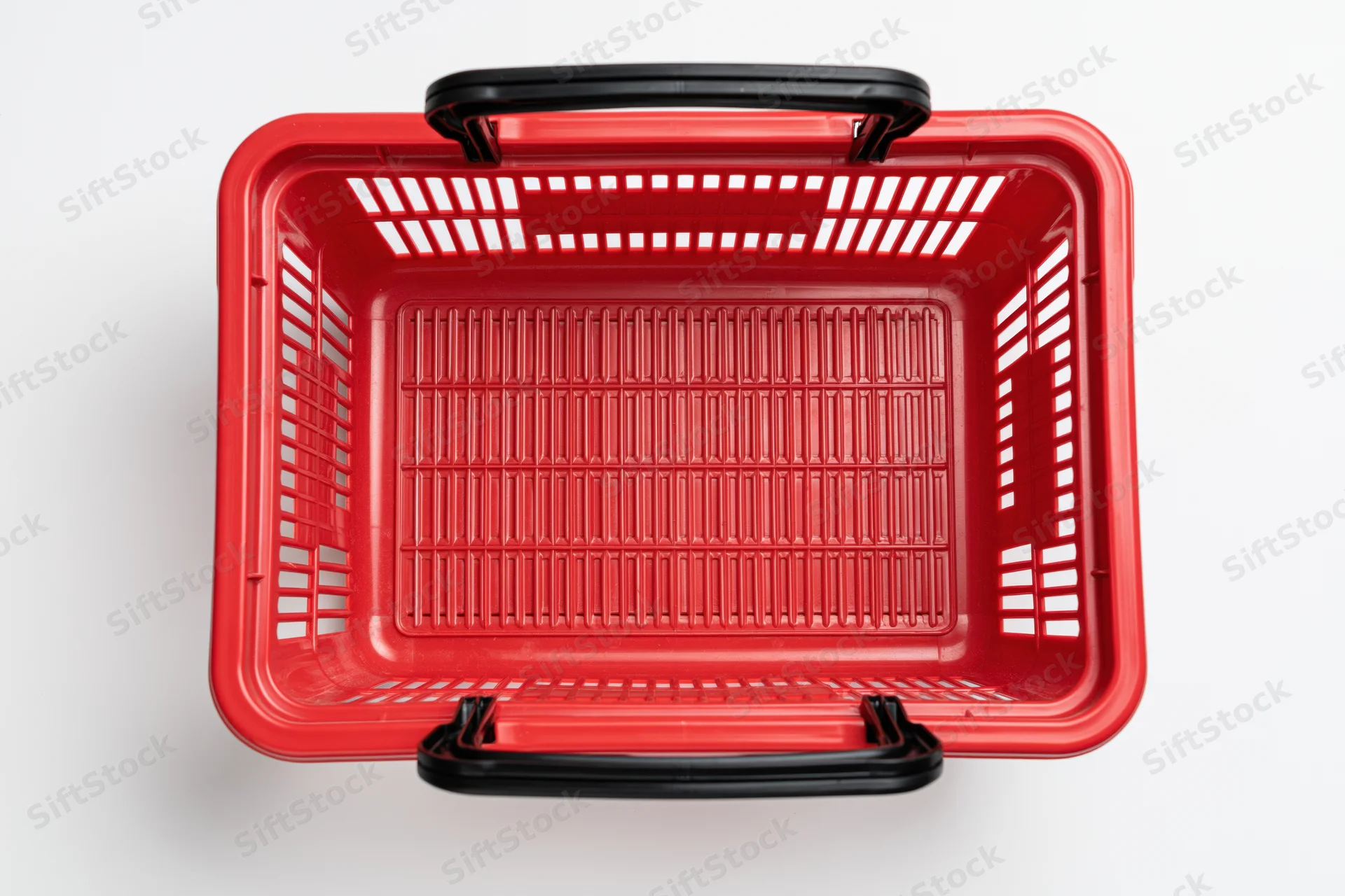 Empty red plastic shopping basket with black handles on white background
