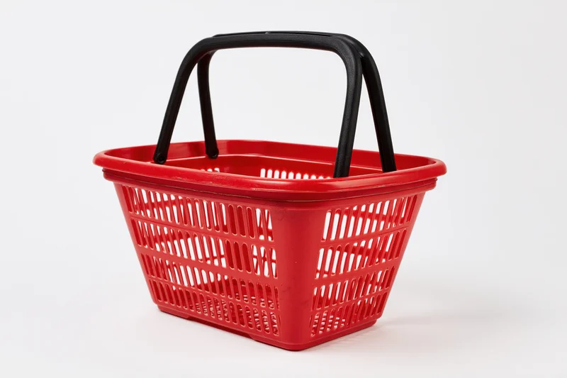 Red plastic shopping basket with black handles on white background