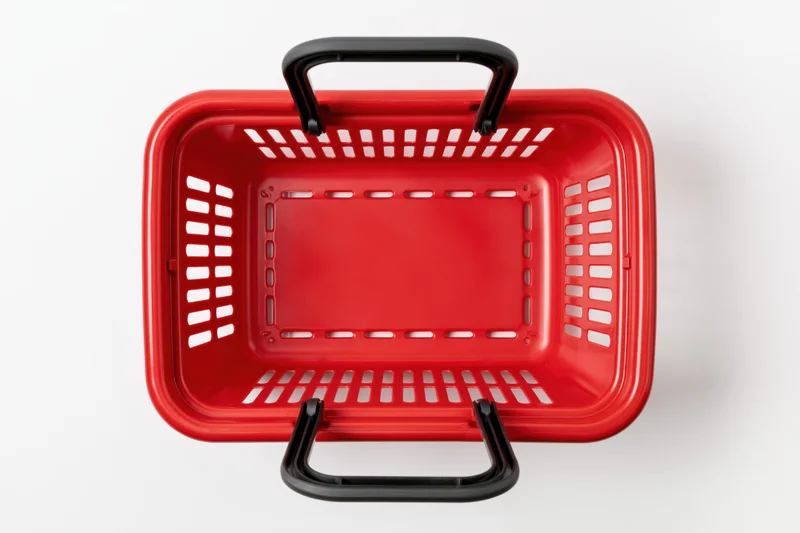 Empty red plastic shopping basket with black handles on white background