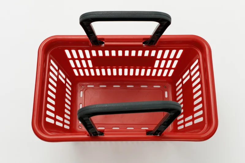 Empty red plastic shopping basket with black handles viewed from above on white background