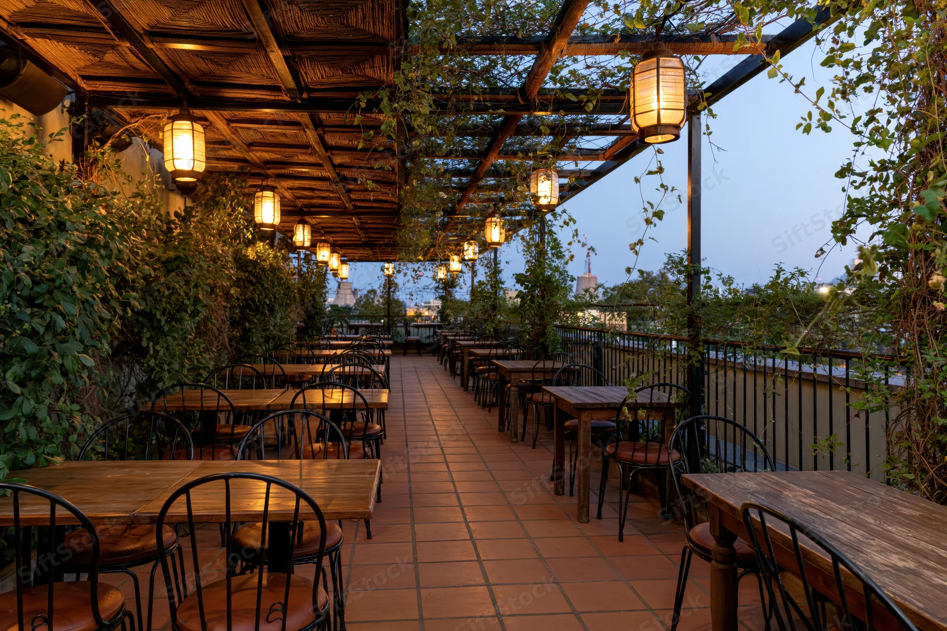Empty rooftop restaurant terrace with wooden tables and hanging lanterns at dusk