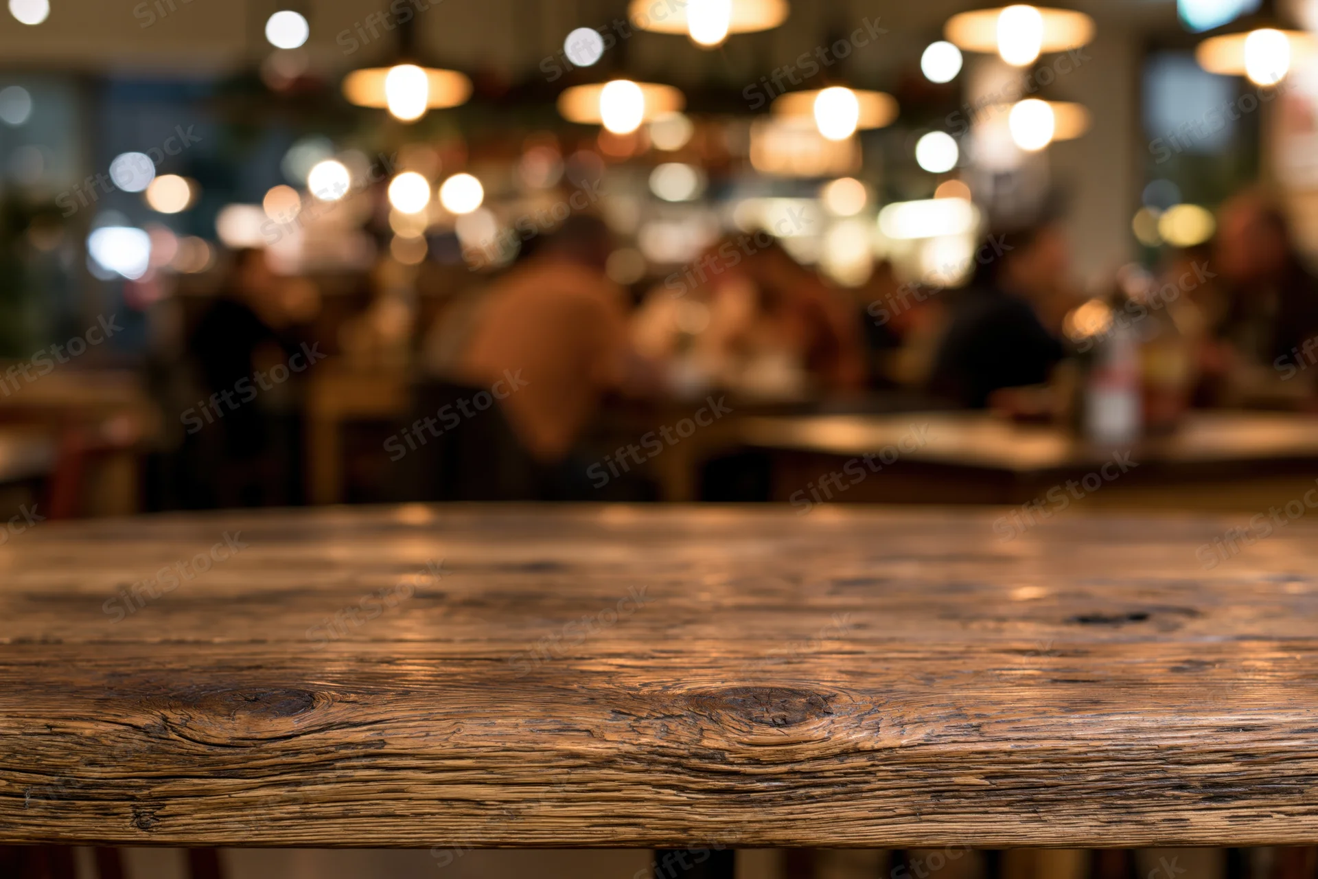 Rustic wooden table surface in sharp focus with blurred restaurant interior and patrons in background