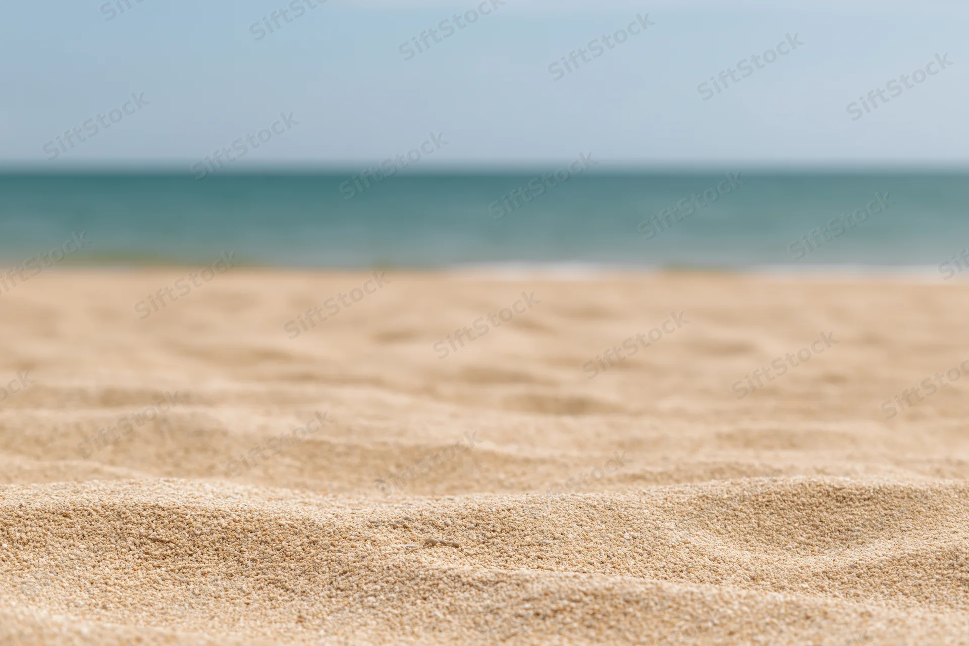 Close-up of textured sand on a beach with ocean in the background